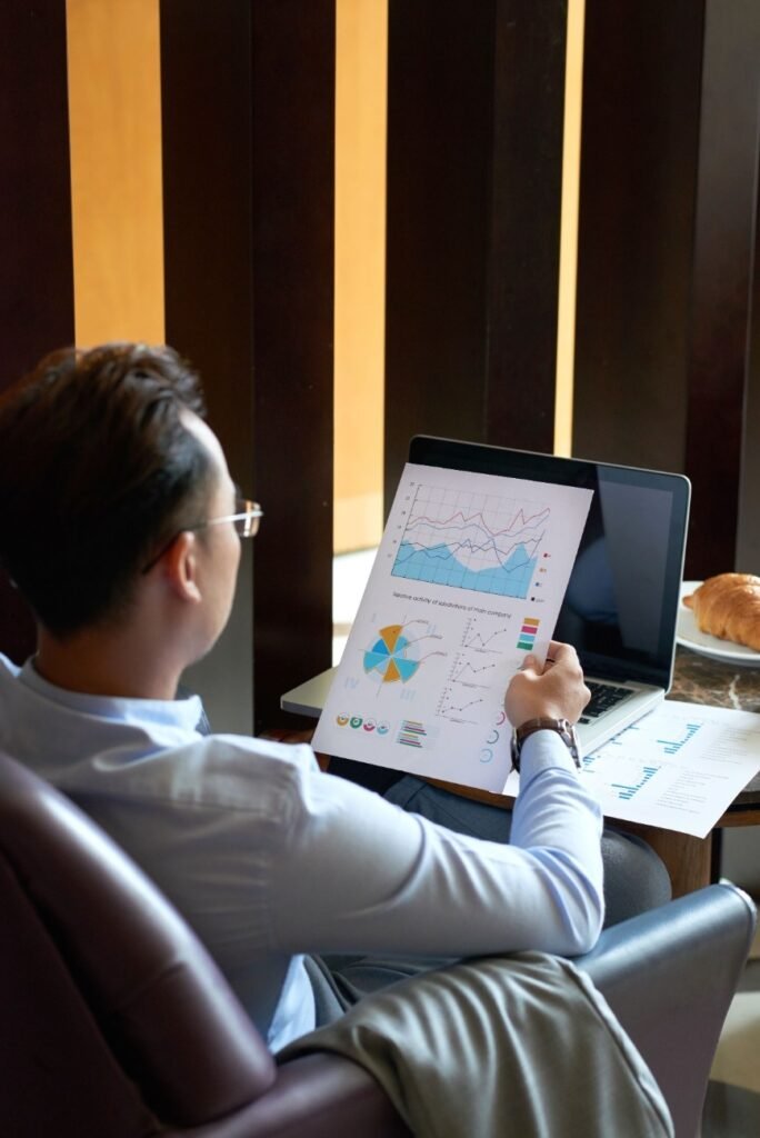 rear-view-man-seated-armchair-cafe-analyzing-diagrams-charts-before-presentation-min (1) Using RSI and MACD tools from technical analysis